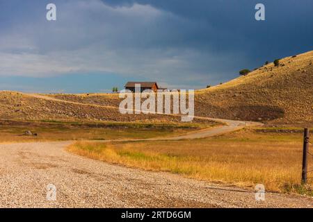 Lumière avant une tempête sur les fermes du sud-ouest du Montana avec la chaîne de montagnes Gallatin et la forêt nationale au loin. Agriculture de grain et de foin. Banque D'Images