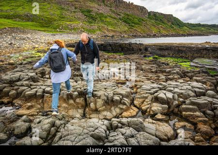 Un couple d'hommes et de femmes marchant sur de grands rochers érodés sur l'île de Skye, en Écosse. Banque D'Images