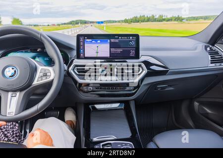 Belle vue de la femme pilote conduisant la nouvelle BMW iX3 M Sport noir voiture modèle électrique sur l'autoroute. Suède. Banque D'Images