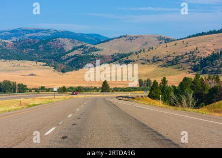 Route panoramique dans le Montana, entre la Butte, Montana et le parc national des Glaciers dans le Nord-Ouest du Montana. Pas d'arbres sur des kilomètres et les paysages de champs de foin. Banque D'Images