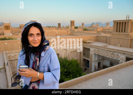 Yazd, Iran - 19 juin 2022 : Femme touriste caucasienne regard à la pose de la caméra boire du café persan dans un café traditionnel sur le toit Relax profiter panoramique v Banque D'Images