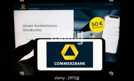 Personne détenant un smartphone avec le logo de la société financière allemande Commerzbank AG sur l'écran devant le site Web. Concentrez-vous sur l'affichage du téléphone. Banque D'Images