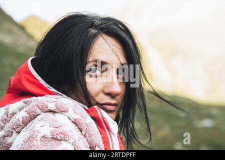 Close up caucasien brunette cheveux noirs femme dans la nature en pyjama regard confortable à la caméra naturelle avec des racines de cheveux gris exposées. Homme de mouvement d'image de femme naturelle Banque D'Images