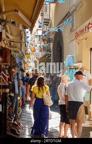 La vue le long de la via S Cesareo, une ruelle étroite bordée de boutiques touristiques dans le centre de Sorrente, en Italie. Sorrente est une ville côtière du sud-ouest de l'Italie, face à la baie de Naples sur la péninsule de Sorrente. Perché au sommet des falaises qui séparent la ville de ses ports de plaisance animés, il est connu pour ses vues panoramiques sur l'eau et la Piazza Tasso, une place bordée de cafés. Banque D'Images