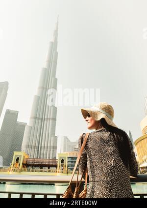 Dubaï, Émirats Arabes Unis - 11th octobre 2022 : touriste moderne, femme qui regarde la tour de Burj Khalifa contre un ciel blanc trouble, Dubaï, Émirats Arabes Unis Banque D'Images