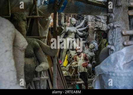 Un artisan en argile âgé crée l'idole en argile de la déesse hindoue Durga à l'intérieur de son atelier d'art en argile avant le plus grand festival Bengalis Durga Puja à Kolkata. Artistes d'argile de Kumartuli (quartier traditionnel des potiers dans le nord de Kolkata), qui fabrique et vend les idoles d'argile de divers dieux avant les saisons de fête qui comprend Ganesh Chaturthi (culte de la divinité hindoue à tête d'éléphant Seigneur Ganesha), Viswakarma puja (culte du dieu hindou de l'ingénierie) et le plus grand festival Bengalis Durga Puja (culte de la déesse hindoue Durga). Banque D'Images