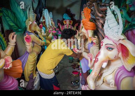 Un artisan peint l'œil d'une idole d'argile du seigneur de divinité hindoue Ganesha avant le festival Ganesh Chaturthi à Kolkata. Artistes d'argile de Kumartuli (quartier traditionnel des potiers dans le nord de Kolkata), qui fabrique et vend les idoles d'argile de divers dieux avant les saisons de fête qui comprend Ganesh Chaturthi (culte de la divinité hindoue à tête d'éléphant Seigneur Ganesha), Viswakarma puja (culte du dieu hindou de l'ingénierie) et le plus grand festival Bengalis Durga Puja (culte de la déesse hindoue Durga). Banque D'Images