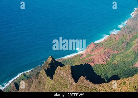 Vue panoramique depuis les falaises verdoyantes couvertes de montagne de la côte de Napali le long du Kalalau Trail sur l'île hawaïenne de Kauai, avec le calme, bleu... Banque D'Images