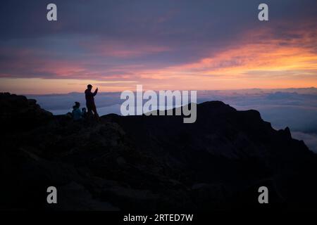 Famille sur un sommet de montagne au-dessus des nuages à Haleakala regarder le lever du soleil sur la côte Pacifique Banque D'Images