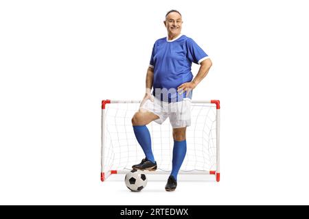 Portrait en longueur d'un homme mûr en maillot de football posant devant un but minin isolé sur fond blanc Banque D'Images