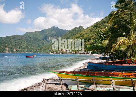 Vue panoramique sur la côte des bateaux de pêche traditionnels à pirogue échoués le long de la rive du petit village de Scotts Head dans la baie de Soufrière sur l'île... Banque D'Images