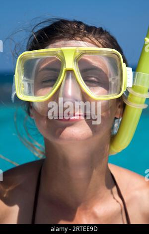 Gros plan d'une jeune femme portant un équipement de plongée en apnée avec les yeux fermés et un sourire de rêve sur son visage à Stingray City (un banc de sable populaire au large ... Banque D'Images