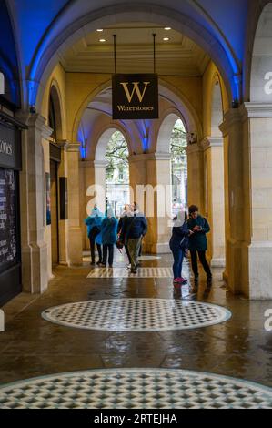 LONDRES - 24 avril 2023 : Découvrez le charme de Londres tandis que les amateurs de shopping trouvent refuge sous la pluie sous les arches historiques de la librairie Waterstones. Banque D'Images