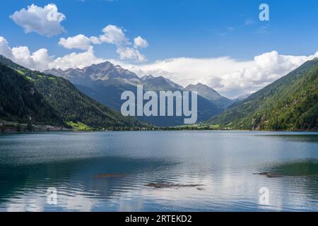 Lac alpin suisse dans les montagnes, Poschiavo (Miralago), Suisse. Les sommets du massif de la Bernina en arrière-plan. ciel bleu avec des nuages. Banque D'Images