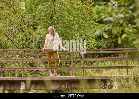 Femme mature debout sur le pont dans la nature Banque D'Images