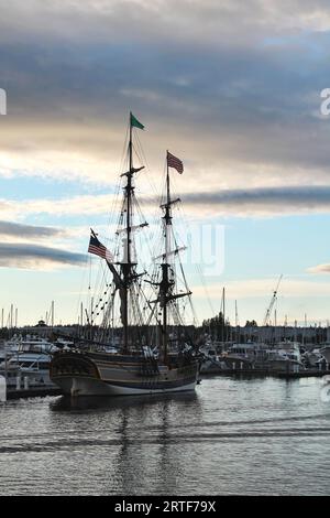 Le grand voilier Lady Washington se trouve à l'ancre dans un port du nord-ouest du Pacifique avec ses mâts et son gréement en silhouette contre le coucher du soleil du soir Banque D'Images