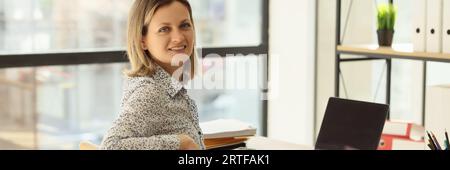 Le Manager s'assoit sur son lieu de travail au bureau et regarde la caméra. Banque D'Images