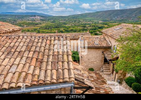 Dans le quartier historique de Lacoste, en Provence, les vieilles maisons traditionnelles en pierre aux toits de tuiles surplombent la campagne française luxuriante, avec le village de Bonnieux visibl Banque D'Images