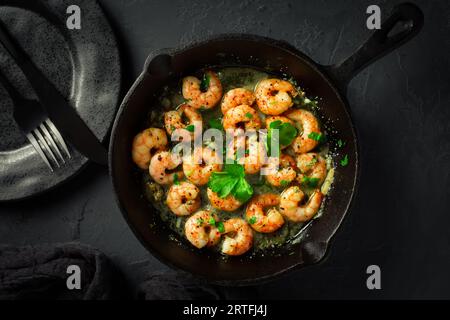 Rôtir les crevettes dans une poêle avec des herbes et de l'ail Banque D'Images