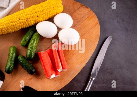 ingrédients de la salade de bâtonnets de crabe : surimi, œufs, maïs, concombre et mayonnaise sause sur planche de kithen. Délices de fruits de mer. Banque D'Images