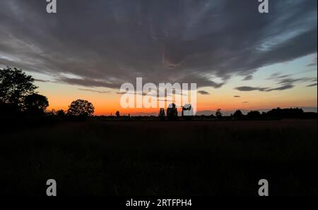 Un coucher de soleil moelleux et atmosphérique projette des ombres sur un paysage rural tranquille. Banque D'Images