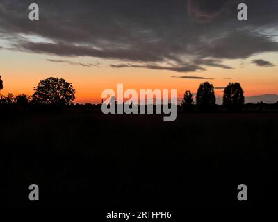 Un coucher de soleil moelleux et atmosphérique projette des ombres sur un paysage rural tranquille. Banque D'Images