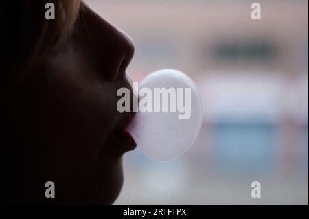 Berlin, Allemagne. 27 août 2023. Un enfant forme une bulle de chewing-gum avec sa bouche. (Scène posée) crédit : Annette Riedl/dpa/Alamy Live News Banque D'Images
