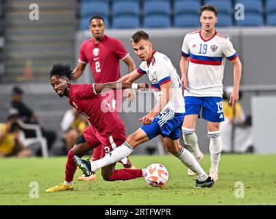 Al Wakrah. 13 septembre 2023. Yusuf Abdurisag (à gauche) du Qatar défie Artem Makarchuk de Russie lors du match amical de football entre le Qatar et la Russie au stade Al-Janoub à Al-Wakrah, au sud de Doha, Qatar, le 12 septembre 2023. Crédit : Nikku/Xinhua/Alamy Live News Banque D'Images
