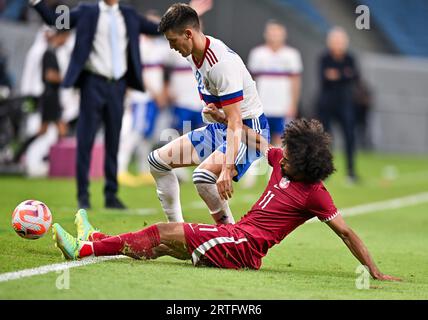 Al Wakrah. 13 septembre 2023. Akram Hassan Afif (à droite) du Qatar affronte Daniil Khlusevich de Russie lors du match amical de football entre le Qatar et la Russie au stade Al-Janoub à Al-Wakrah, au sud de Doha, Qatar, le 12 septembre 2023. Crédit : Nikku/Xinhua/Alamy Live News Banque D'Images