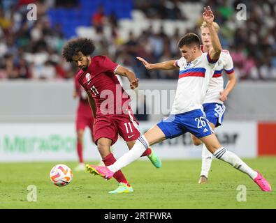 Al Wakrah. 13 septembre 2023. Akram Afif (à gauche) du Qatar affronte Daniil Khlusevich de Russie lors du match amical de football entre le Qatar et la Russie au stade Al-Janoub à Al-Wakrah, au sud de Doha, Qatar, le 12 septembre 2023. Crédit : Nikku/Xinhua/Alamy Live News Banque D'Images