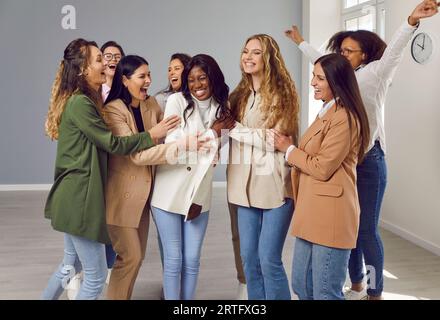 Groupe de femmes heureuses et diverses amies ou collègues se tenant debout dans un brut sur fond gris. Banque D'Images