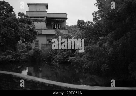 Une majestueuse maison de deux étages située sur les rives d'une rivière tranquille en niveaux de gris Banque D'Images