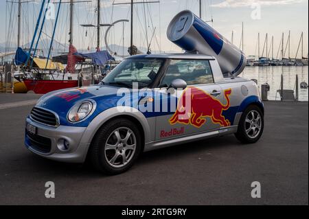 Lausanne, Canton de Vaud, Suisse - 20 août 2023 : Red Bull annonce une voiture Mini Cooper avec logo. Bidon de boisson énergisante Red Bull géant sur le roo de la voiture Banque D'Images