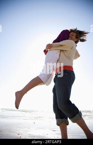 Jeune couple qui joue et se débrouille sur une plage Banque D'Images