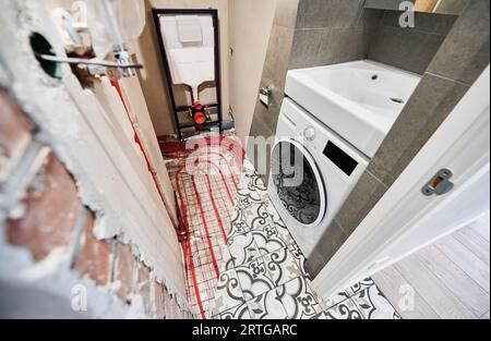 Comparaison des toilettes avant et après rénovation. Ancien appartement toilettes avec tuyaux de chauffage au sol et nouvelle salle de toilette rénovée avec machine à laver. Banque D'Images