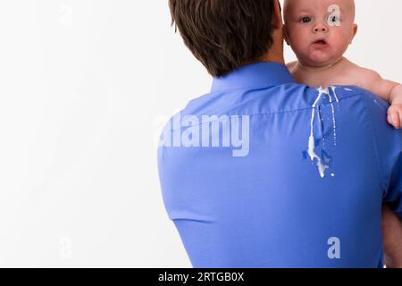 Vue arrière d'un homme tenant un bébé avec du vomi sur son dos et l'épaule Banque D'Images