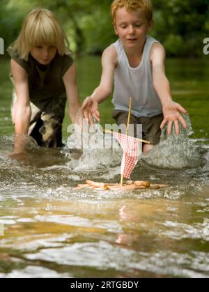 Deux jeunes garçons, dans un cours d'eau, projections d'eau vers un modèle série Banque D'Images