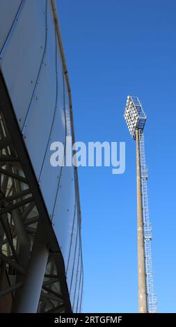 un mât de projecteur haut et un fragment de la structure du stade contre le ciel bleu, éléments de l'infrastructure sportive urbaine et de l'architecture Banque D'Images