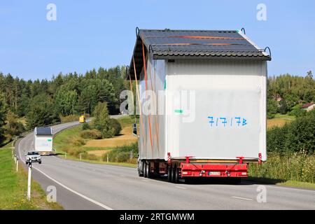 Deux transports de charge exceptionnels transportant des cabines préfabriquées dans la circulation routière, assistance véhicule pilote. Salo, Finlande. 7 septembre 2023. Banque D'Images