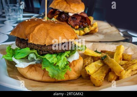 Hamburger de bœuf juteux et appétissant entre un petit pain frais et de la laitue servi avec des frites croustillantes Banque D'Images