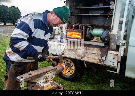 Porteur de chevaux, Craig Robotown utilisant une enclume portable et un four à gaz monté sur camion mobile pour secouer les fers à cheval tout en travaillant dans une école d'équitation près de Sorell, Tasmanie Banque D'Images