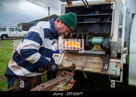 Porteur de chevaux, Craig Robotown utilisant une enclume portable et un four à gaz monté sur camion mobile pour secouer les fers à cheval tout en travaillant dans une école d'équitation près de Sorell, Tasmanie Banque D'Images