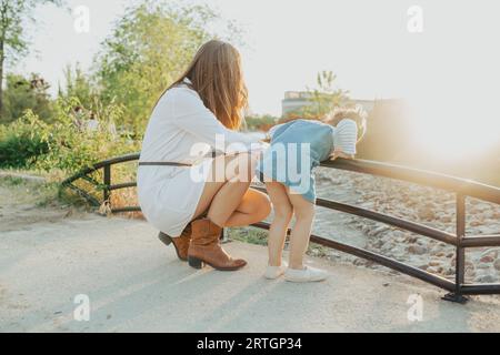 Vue latérale de la jeune femme et de la petite fille se pliant balusez et regardez le jet d'eau rapide par beau temps dans le parc Banque D'Images