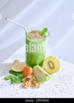 D'en haut de smoothie vert sain avec des graines de sésame servi sur la table avec des fruits et des carottes sur fond blanc en studio Banque D'Images