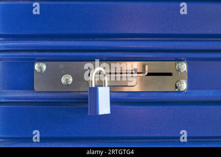 Un verrou bleu sur une barrière métallique dans une salle de stockage Banque D'Images