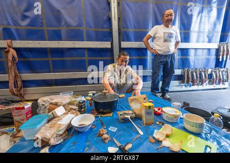 13 septembre 2023, Hesse, Gräfenhausen : les chauffeurs de camion du Tadjikistan sont assis et debout dans le parking de la zone de service de Gräfenhausen à une table à manger de fortune sur la zone de chargement d'un camion, qui sert également de camp de nuit. Les chauffeurs, qui viennent de plusieurs pays d’Europe de l’est, attendent dans leurs camions sur le parking de la zone de service de Gräfenhausen depuis près de deux mois, en attendant le paiement de leur salaire. Photo : Boris Roessler/dpa Banque D'Images