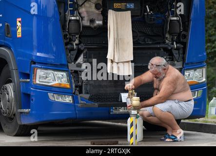 13 septembre 2023, Hesse, Gräfenhausen : un chauffeur de camion remplit une bouteille d'eau potable sur le parking de la zone de service de Gräfenhausen. Les chauffeurs, qui viennent de plusieurs pays d’Europe de l’est, attendent dans leurs camions sur le parking de la zone de service de Gräfenhausen depuis près de deux mois, en attendant le paiement de leur salaire. Photo : Boris Roessler/dpa Banque D'Images