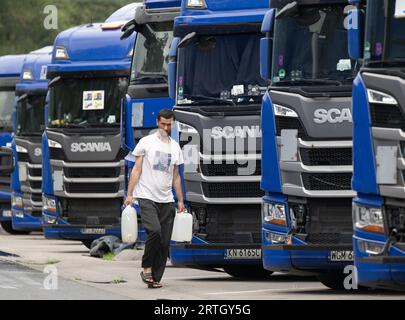 13 septembre 2023, Hesse, Gräfenhausen : un chauffeur de camion transporte des bidons d'eau à son véhicule sur le parking de la zone de service de Gräfenhausen. Les chauffeurs, qui viennent de plusieurs pays d’Europe de l’est, attendent dans leurs camions sur le parking de la zone de service de Gräfenhausen depuis près de deux mois, en attendant le paiement de leur salaire. Photo : Boris Roessler/dpa Banque D'Images