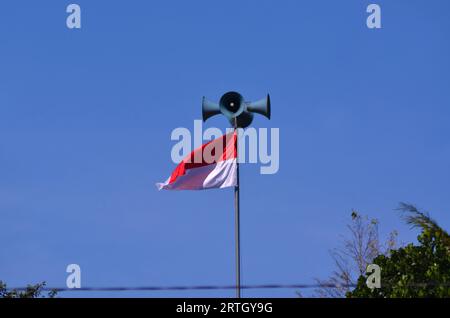 drapeau rouge et blanc monté sur un poteau de haut-parleur sur un fond de ciel bleu. Banque D'Images