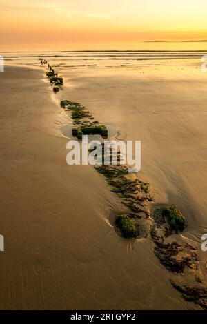 Coucher de soleil sur la plage de Harlech avec ciel bleu et mer calme. Banque D'Images